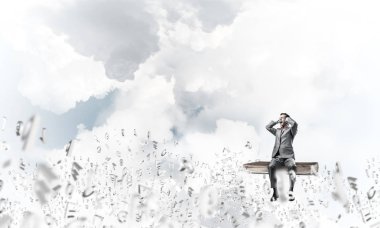 Genç kitap üzerinde oturan ve avuç içi gözlerle kapsayan bir işadamı şok