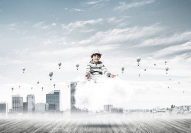 Genç küçük çocuk gözleri koruma kapalı ve seyir sırasında cityscape manzaralı cloud üzerinde meditasyon ve aerostats arka plan üzerinde uçan konsantre.