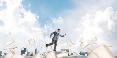 Takım elbise ile telefonu elinde kitap Clear sky ile arka plan üzerinde uçan arasında çalışan iş adamı. Karışık teknik.