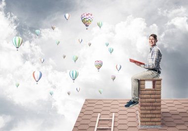 Elinde kırmızı kitap ile evin baca rahat oturan genç adam