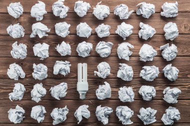 Akkor ampul ve buruşuk beyaz kağıt topları kahverengi ahşap tablo