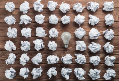 Akkor ampul ve buruşuk beyaz kağıt topları kahverengi ahşap tablo