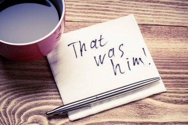 Kahve fincanı dolma kalem ve peçeteyle ahşap masada kelimeler.