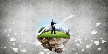 Takım elbiseli genç işadamının uçan kağıt uçakların arasında elinde büyük beyaz bir okla uçan adada dikilirken ve arka planda koyu gri bir duvara yaslanırken kavramsal görüntüsü..