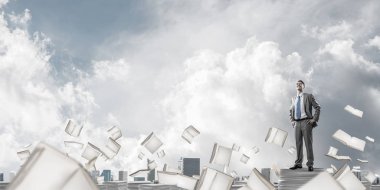 Kendine güvenen işadamı belgeleri kitap Clear sky ile arka plan üzerinde uçan arasında yığını üzerinde takım elbise ayakta. Karışık teknik.