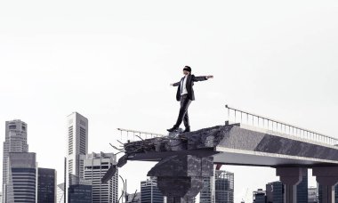 Gizli tehditlerin ve risklerin sembolü olarak beton köprüde gözü kapalı yürüyen bir iş adamı. Arka planda şehir manzarası. 3B görüntüleme.