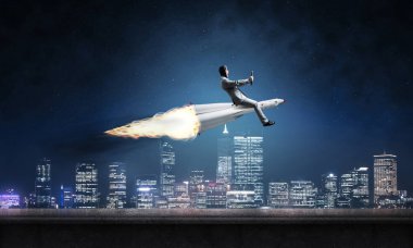 Arka plan üzerinde gece cityscape ve mavi gökyüzü ile roket üzerinde uçan takım elbiseli genç işadamı kavramsal görüntü.