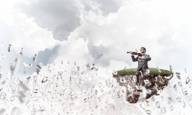 Genç adam takım elbise ve Adası'nda oturan ve Keman çalmaya gözlük