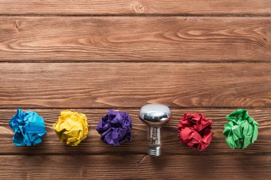 Akkor ampul ve buruşuk beyaz kağıt topları kahverengi ahşap tablo