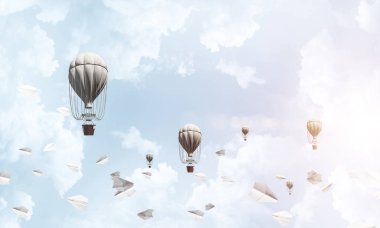 Renkli aerostats kağıt uçaklar arasında ve mavi bulutlu gökyüzü üzerinde uçan. 3D render.