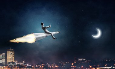 Arka plan üzerinde gece cityscape ve mavi gökyüzü ile roket üzerinde uçan takım elbiseli genç işadamı kavramsal görüntü.
