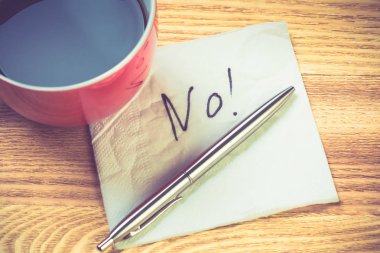 Kahve fincanı dolma kalem ve peçeteyle ahşap masada kelimeler.