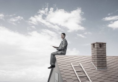 Elinde kırmızı kitap ile ev oturan takım elbiseli genç işadamı