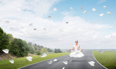 Genç kadın gözleri koruma kapalı ve seyir ile güzel ve nefes kesici manzara arka plan üzerinde bulut yukarıda yolun üzerinde meditasyon sırasında konsantre.