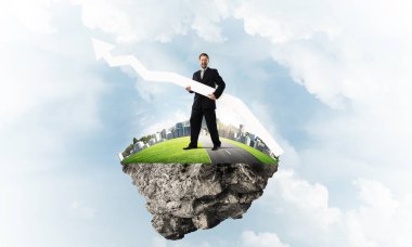 Takım elbiseli genç işadamı, elinde kocaman beyaz bir pankartıyla uçan adada duruyor. Arka planda bulutlu bir gökyüzü manzarası var.