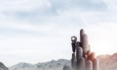 İş kadını kafasına silah tutmak yerine eski bir Tv ile takım elbiseli güzel manzara ile taş sütunlar tepesinde dururken arka plan üzerinde çarpı işareti.