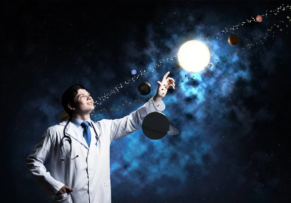 自信而成功的男医生穿着白色医服站在外太空 与太阳系对接 背景有黑暗的空间视野 — 图库照片