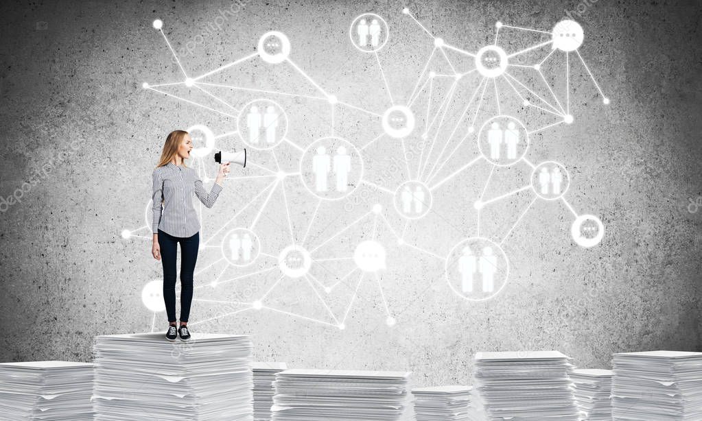 Woman in casual wear with speaker in hand standing on pile of documents with social network structure on background. Mixed media.