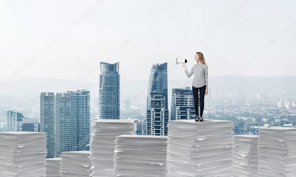 Woman in casual clothing standing on pile of documents with speaker in hand with cityscape on background. Mixed media.