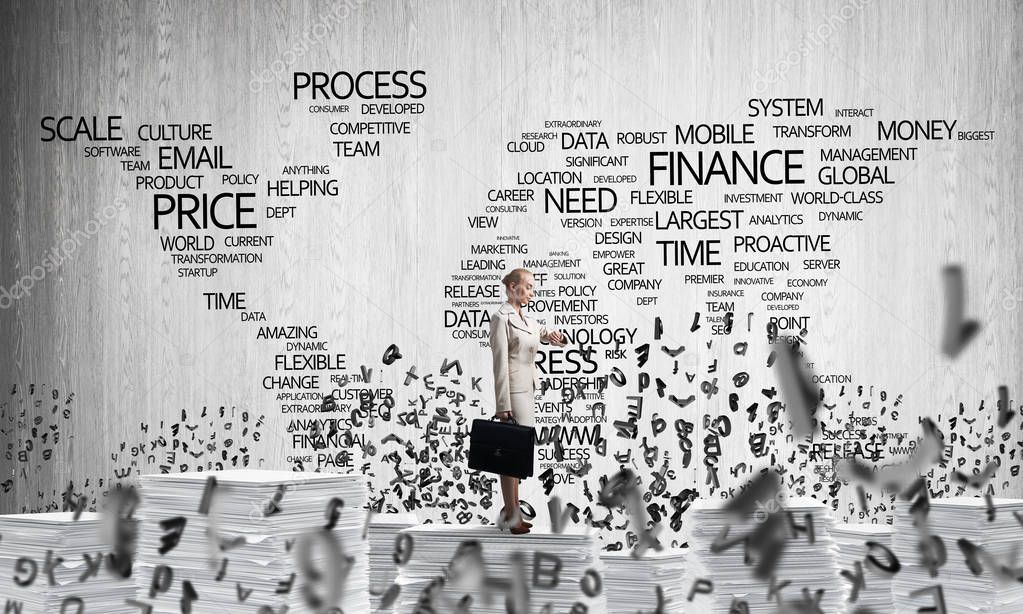 Business woman in suit standing among flying letters with business-related terms in form of world map on background. Mixed media.