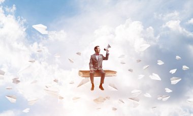 Kitap üzerinde oturan ve duygusal megafon içinde çığlık genç işadamı