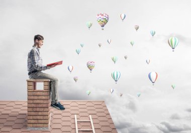 Elinde kırmızı kitap ile evin baca rahat oturan genç adam