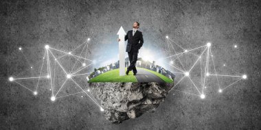 Takım elbiseli genç bir işadamı uçan adada dikiliyor ve elinde kocaman beyaz bir afişle arka planda gri siyah bir duvarla yukarı bakıyor..