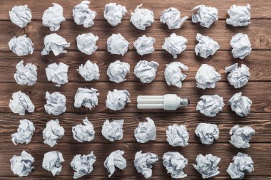 Akkor ampul ve buruşuk beyaz kağıt topları kahverengi ahşap tablo