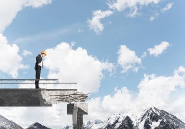 Genç takım elbiseli mühendis ve arka plan üzerinde hava ve Doğa Manzaralı Tamirhane üzerinde dururken bakıyordu kask. 3D render.