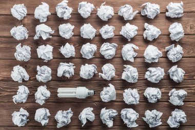 Akkor ampul ve buruşuk beyaz kağıt topları kahverengi ahşap tablo