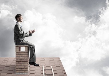 Elinde cep telefonu ile evin baca oturan genç işadamı