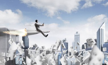 Kağıtları ile modern cityscape gökdelenler ve mavi gökyüzü ile arka plan üzerinde uçan arasında roket üzerinde uçan takım elbiseli Genç ve mutlu işadamı kavramsal görüntü.