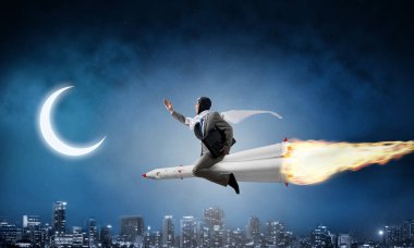 Arka plan üzerinde moon ile gece cityscape ve mavi karanlık gökyüzü ile roket üzerinde uçan takım elbiseli genç işadamı kavramsal görüntü.