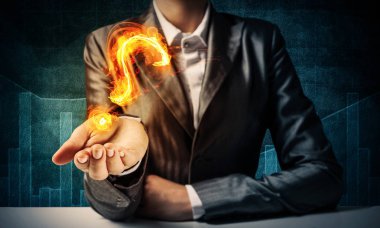 İşadamı elbiseli yanan soru işareti ile karanlık artalanları elinde sunma kırpılmış görüntü.