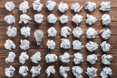 Akkor ampul ve buruşuk beyaz kağıt topları kahverengi ahşap tablo