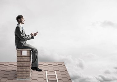 Elinde cep telefonu ile evin baca oturan genç işadamı