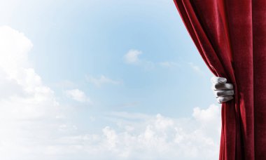 İnsan elinde eldiven mavi gökyüzü arka plan üzerinde kırmızı kadife perde açılır