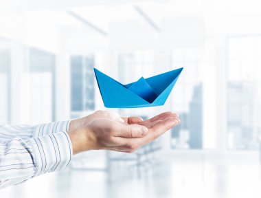 İşadamlarının elinde kağıttan gemi tutması başarının sembolü. Karışık ortam