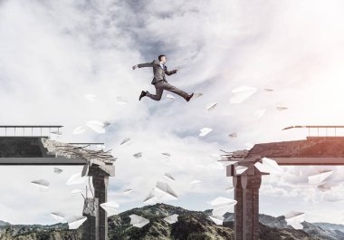İşadamı, sorunların üstesinden gelmenin sembolü olarak uçan kağıt uçaklar arasında köprüdeki boşluktan atlıyor. Arka planda güneş ışığı ve doğa manzaralı gökyüzü. 3B görüntüleme.