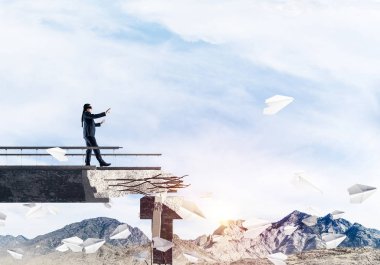 Gizli tehditlerin ve risklerin sembolü olarak beton köprüde gözü kapalı yürüyen bir iş adamı. Arka planda gökyüzü ve doğa manzarası. 3B görüntüleme.