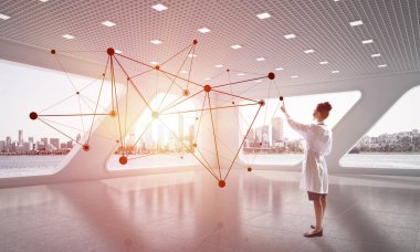 Duran beyaz hastane ofis içinde sosyal ağ yapısı ile çalışan beyaz tıbbi üniformalı genç kadın doktor. Tıbbi sanayi ve çağdaş teknolojileri