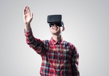 Ekose desenli gömlek gri arka plan karşı sanal kask giymiş genç adam