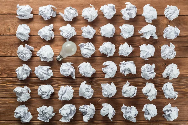 Bombilla Incandescente Bolas Papel Blanco Arrugadas Sobre Mesa Madera Marrón —  Fotos de Stock