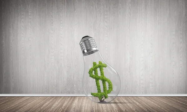 Glass lightbulb with green dollar symbol inside in empty room with grey wall on background. 3D rendering.