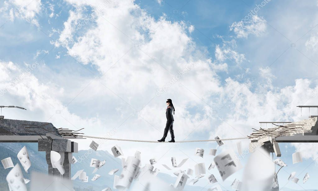 Businessman walking blindfolded on rope among flying papers and above huge gap in bridge as symbol of hidden threats and risks. Nature view on background. 3D rendering.