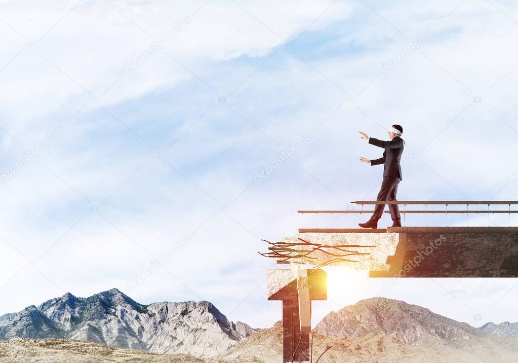 Businessman walking blindfolded on concrete bridge with huge gap as symbol of hidden threats and risks. Skyscape and nature view on background. 3D rendering.