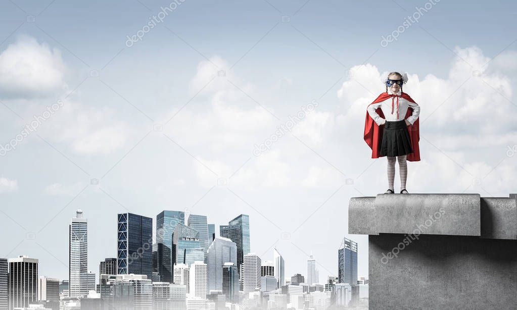 Young girl in superhero costume standing on building roof. Mixed media