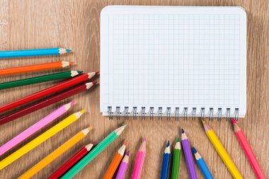 Ahşap masa blackground yaratıcılık kavram olarak üzerinde boş not defteri ve renk kalemler