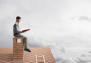 Elinde kırmızı kitap ile evin baca rahat oturan genç adam