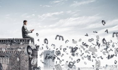 Elinde smartphone ile üst yapı üzerinde oturan genç işadamı